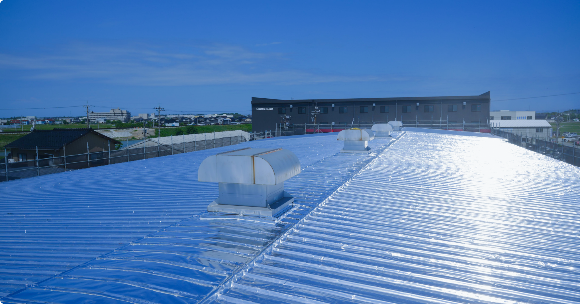 工場の屋根に遮熱材を施工している作業の様子