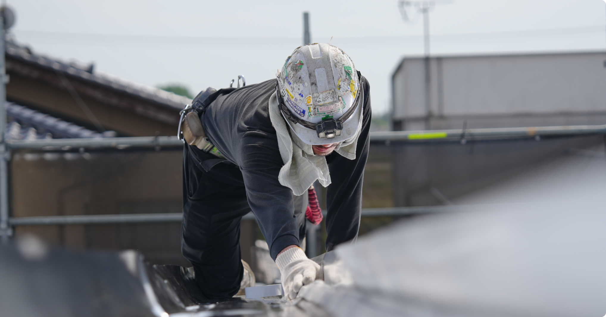 工場の屋根で遮熱材施工を行う作業員